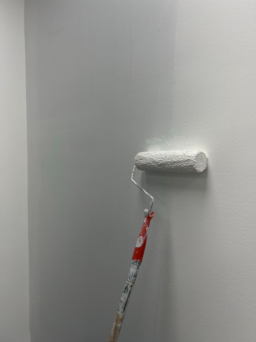 Paint roller on a freshly painted wall